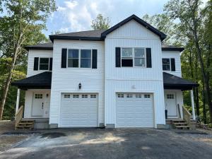 a white house with two garage doors at NEW 3 bedroom - Thoroughbred Farm & Lake Views! in Saratoga Springs