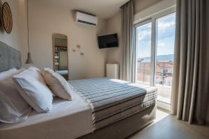 1 dormitorio con cama y ventana grande en Palaia Luxury Suite, en Volos