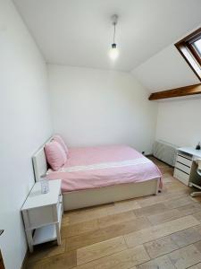- une petite chambre avec un lit rose et un bureau dans l'établissement Jabeen's House Bedroom 2, à Bezons