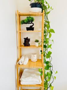 une étagère en bambou avec des serviettes et un bonsaï dans l'établissement Jabeen's House Bedroom 2, à Bezons