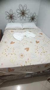 a bed with a white comforter with flowers on it at Casa temporada ilheus in Ilhéus