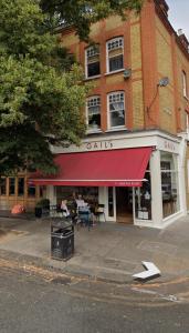 a building with a red awning on a street at Abeville Village Apartment in London