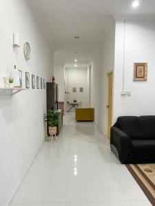 a living room with a black couch and a white floor at Homestay Seri Aman Pasir Puteh 