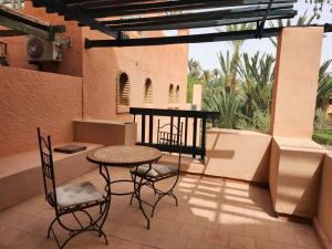 een patio met een tafel en stoelen op een balkon bij Suite dans la palmeraie refaite à neuf grande Terrasse Dar Dmana in Marrakesh