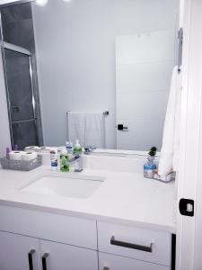 a white bathroom with a sink and a mirror at Peace down the corner in Mission