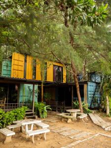 un edificio amarillo con mesas de picnic delante de él en Beach Box Resort at Rimlay Rayong en Rayong