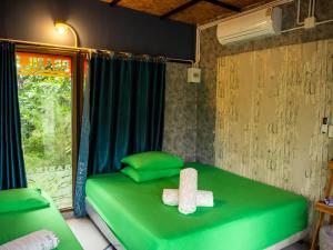 Beach Box Resort at Rimlay Rayong في رايونغ: سرير أخضر في غرفة مع نافذة