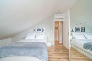 two beds in a bedroom with white walls and wooden floors at NIMA Cozy Stay Mlini in Mlini