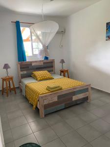 1 dormitorio con 1 cama con edredón amarillo en Au Gré des Alizés - Kaz Ti Plézi, en Cadet