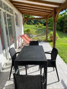 - une table et des chaises noires sur la terrasse dans l'établissement Au Gré des Alizés - Kaz Ti Plézi, à Cadet