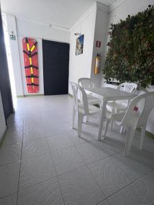 Posada Francelly في سان أندريس: طاولة بيضاء وكراسي في غرفة بها نبات