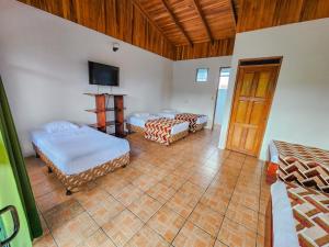 a room with two beds and a flat screen tv at Hotel Sierra Arenal in Fortuna
