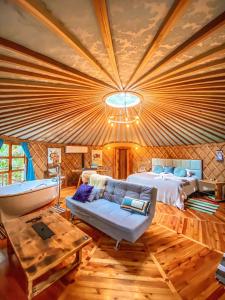 een slaapkamer met een bed, een bank en een tafel bij Solar do Oriente - Yurt Ecovillage in São Joaquim