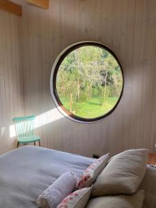 Un dormitorio con una ventana circular y una cama con almohadas en Riberas del Futa, en Valdivia