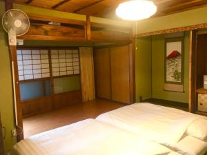 1 dormitorio con 1 cama blanca y ventilador en NOW TRAVEL ShinOsaka, en Osaka