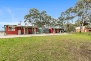 une maison rouge avec une table de pique-nique dans un champ dans l'établissement Clare Valley Cabins, à Clare