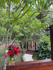 a vase of red roses sitting on a bench with a bridge at Solar do Oriente - Yurt Ecovillage in São Joaquim