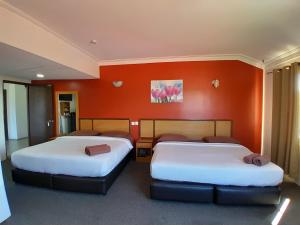 Duas camas num quarto com uma parede laranja em THE ZULEY HERITAGE HOTEL em Kuala Perlis