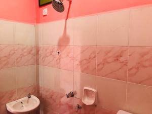 ein rosafarbenes Bad mit einem Waschbecken und einem Urinal in der Unterkunft Chalet Sri Bayu in Kampong Balai Maras