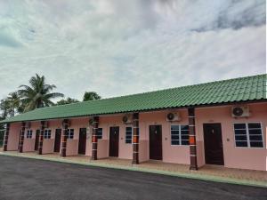 a building with pink doors and a green roof at Chalet Sri Bayu in Kampong Balai Maras