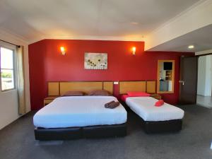 duas camas num quarto com uma parede vermelha em THE ZULEY HERITAGE HOTEL em Kuala Perlis