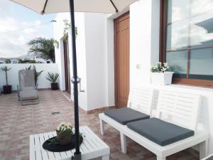 a patio with two white chairs and an umbrella at Casa Isabel in Playa Honda