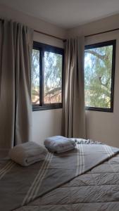1 dormitorio con 2 almohadas en una cama y 2 ventanas en Vid_y_Olivo. Cómodo departamento en el centro de Maipú en Maipú