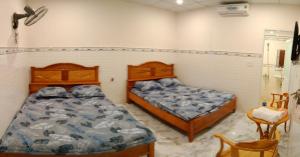 a bedroom with two beds and a chair at Nhà Nghỉ Tuyết Minh in Xóm Mỹ Thanh +3 photos