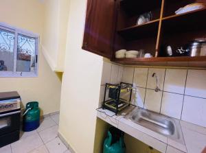 uma cozinha com um lavatório e uma bancada em Complexe BEL AIR em Bafoussam