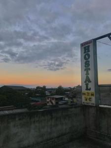 un cartel en un edificio con una puesta de sol en el fondo en Kanoas Hostal, en Puyo
