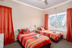 two beds in a room with red curtains and a window at Sue Casa 12 in Margate