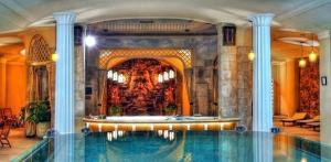 a swimming pool in a building with a fountain at Kranio in Karlovy Vary