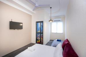 1 dormitorio con 1 cama y TV en la pared en The Bahari Lodge @ Georgetown, en George Town