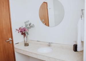 a bathroom sink with a mirror and a vase of flowers at Yellow in San Miguel de Tucumán