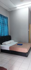 a bedroom with a bed in a room with blue curtains at Sobey Laris Roomstay IMAN GMC in Gua Musang