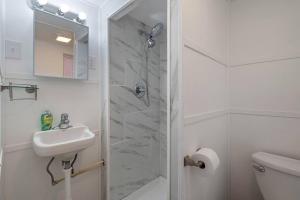 a white bathroom with a shower and a sink at Comfy Cuse home close to SU in Syracuse