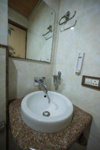 a bathroom with a white sink and a mirror at Rajdarbar Hotel & Banquet, Siliguri in Siliguri