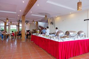 Hưng LongにあるTre Nguồn Thiên Cầm Hotel&Resortの料理人のいる赤いテーブルのあるレストラン