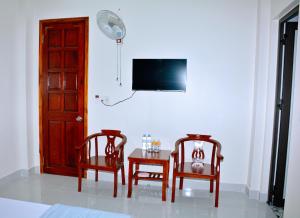 a room with two chairs and a table and a tv at Vinh Airport Hotel in Vinh