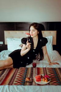 uma mulher sentada numa cama com um prato de comida em Phuong Nam Hotel em Sa Pa