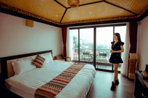 une femme debout dans une chambre d'hôtel avec un lit dans l'établissement Phuong Nam Hotel, à Sa Pa