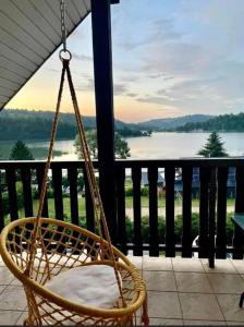 un columpio en un porche con vistas al lago en Apartamenty Na Stoczku nad jeziorem z widokiem na jezioro JACUZZI, en Polańczyk