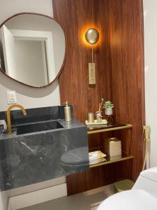 a bathroom with a sink and a mirror at Apart moderno 3 suites 2 vagas de garagem e quadra do mar in Itapema