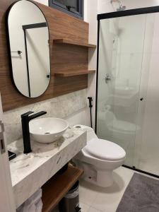 a bathroom with a sink and a toilet and a mirror at Apart moderno 3 suites 2 vagas de garagem e quadra do mar in Itapema