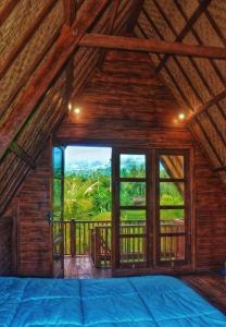 um quarto com uma grande janela numa casa de madeira em triangle cottage bali em Ambengan