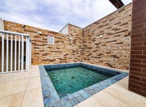 a brick wall with a swimming pool in a courtyard at Ap. c/ piscina 400m praia in Ubatuba