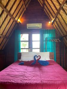 dois cisnes sentados numa cama num quarto em triangle cottage bali em Ambengan