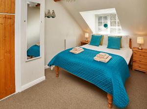 sypialnia z łóżkiem z niebieską pościelą i lustrem w obiekcie Smugglers Rock Cottage w mieście Ravenscar