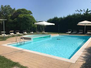 ein großer Pool mit Stühlen und einem Sonnenschirm in der Unterkunft Hotel Doria - Business & Bike Hotel in Ostiglia