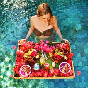 a woman in a pool with a tray of food in the water at Yuni Hotel And Apartment in Da Nang